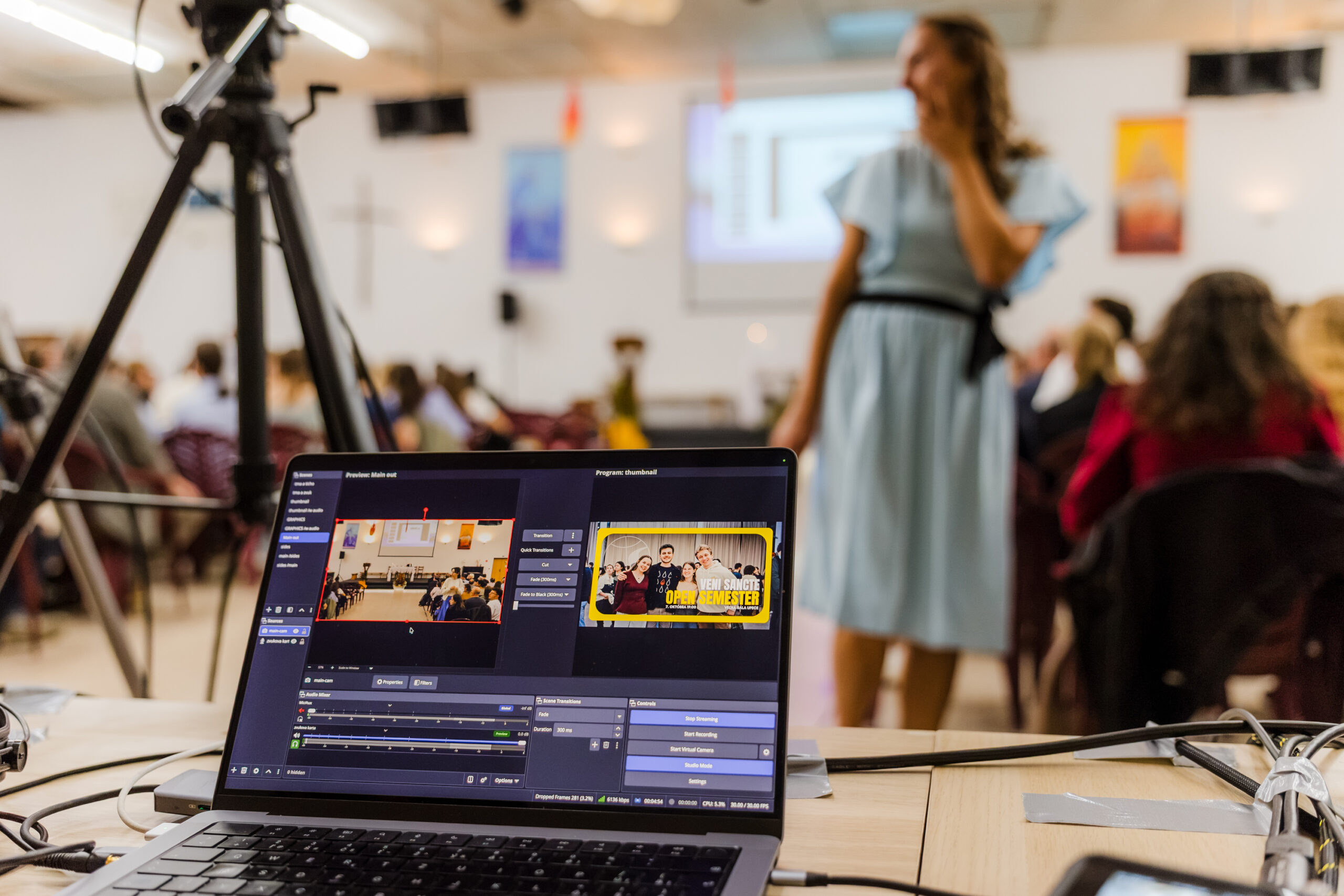 Notebook s vysielacím softvérom a kamera na statíve vo Veľkej sále